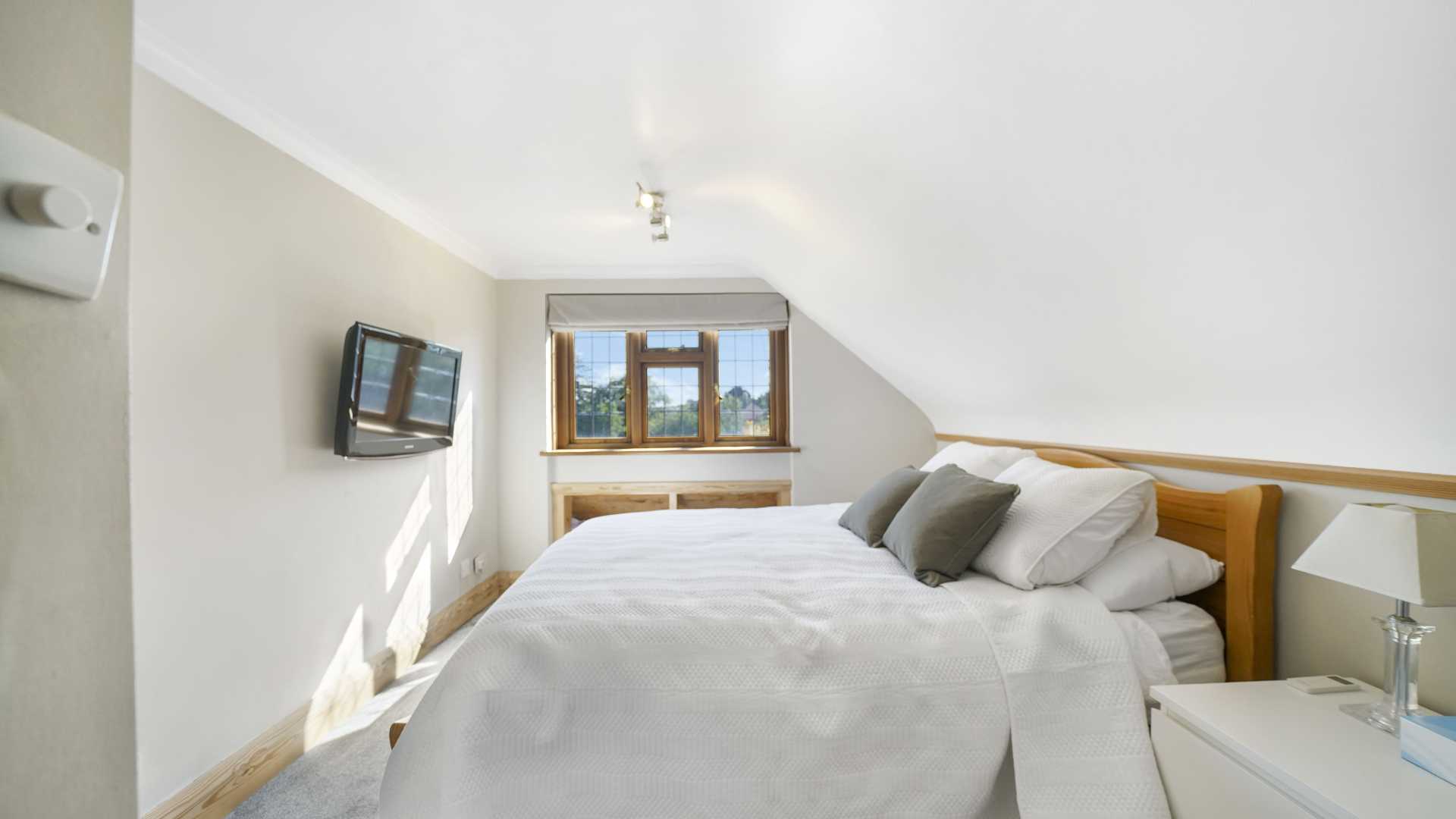 Bright bedroom with double bed, bedside cabinet and open door to hallway
